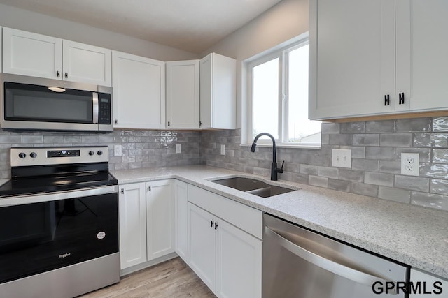 kitchen featuring tasteful backsplash, white cabinetry, appliances with stainless steel finishes, and sink