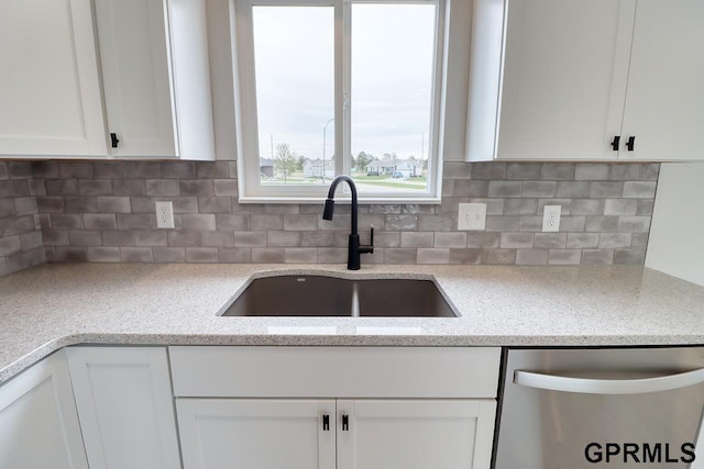 kitchen featuring tasteful backsplash, white cabinetry, sink, and stainless steel dishwasher