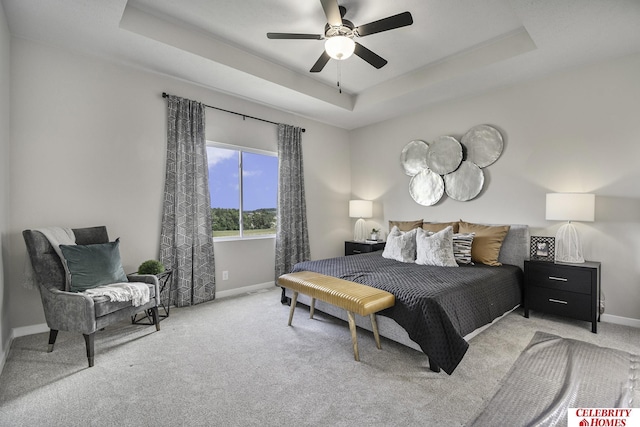 carpeted bedroom with a raised ceiling and ceiling fan