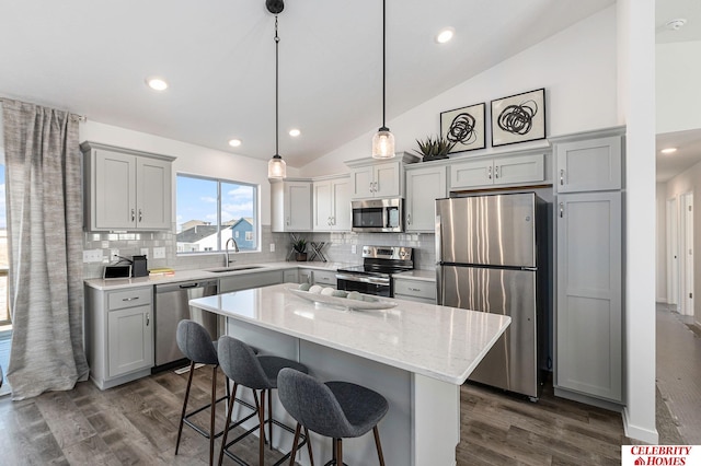 kitchen featuring lofted ceiling, sink, hanging light fixtures, a kitchen island, and stainless steel appliances