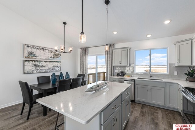 kitchen featuring sink, decorative light fixtures, a center island, vaulted ceiling, and appliances with stainless steel finishes