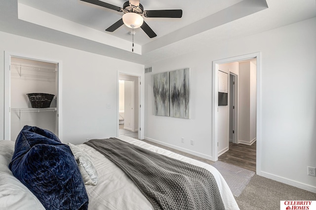 bedroom with a raised ceiling, ceiling fan, and a closet