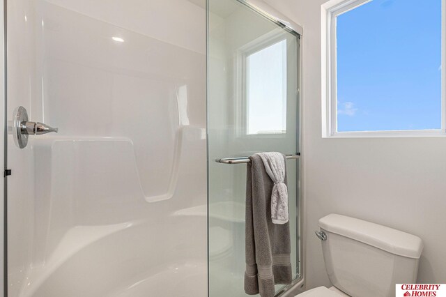 bathroom with a shower with shower door and toilet