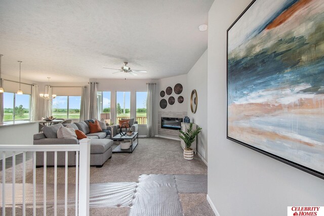 living room featuring a textured ceiling, carpet, and ceiling fan with notable chandelier