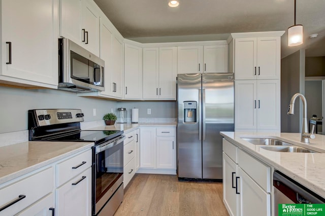 kitchen featuring light stone countertops, light hardwood / wood-style flooring, stainless steel appliances, white cabinets, and sink