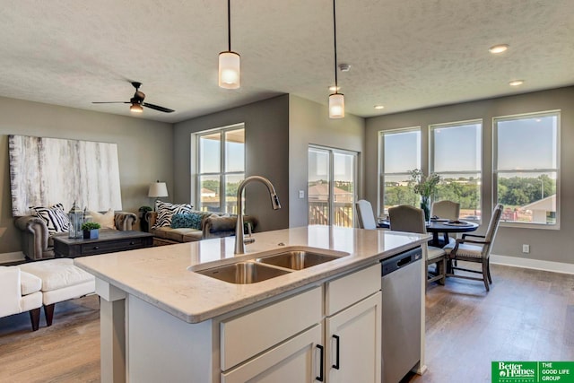 kitchen with white cabinetry, stainless steel dishwasher, hardwood / wood-style floors, pendant lighting, and sink