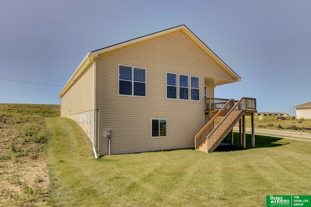 rear view of house featuring a lawn and a wooden deck