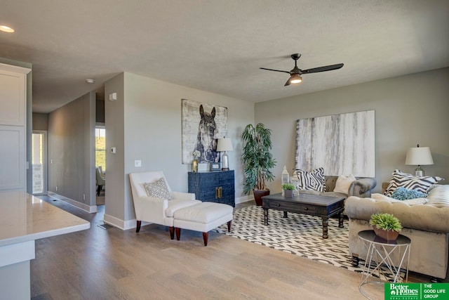 living room with a textured ceiling, wood-type flooring, and ceiling fan