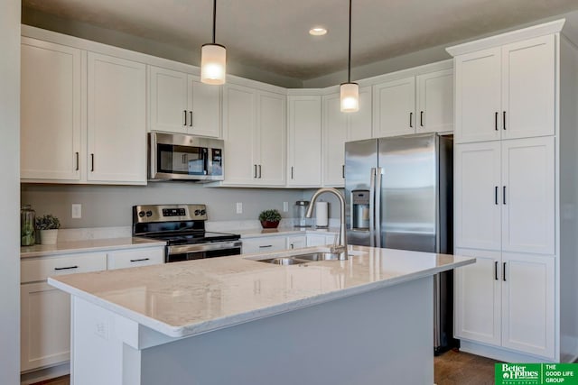 kitchen featuring white cabinets, decorative light fixtures, stainless steel appliances, a kitchen island with sink, and sink