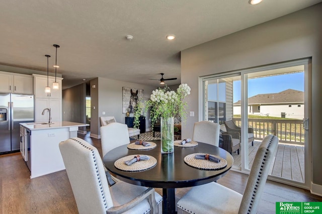 dining area featuring ceiling fan, sink, hardwood / wood-style flooring, and a textured ceiling