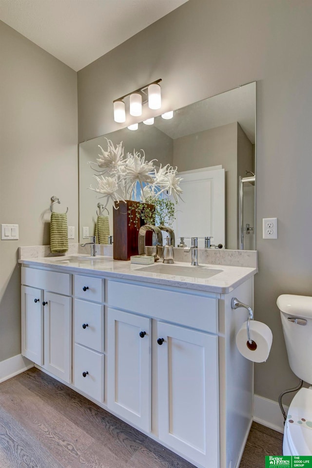 bathroom with dual bowl vanity, toilet, and wood-type flooring