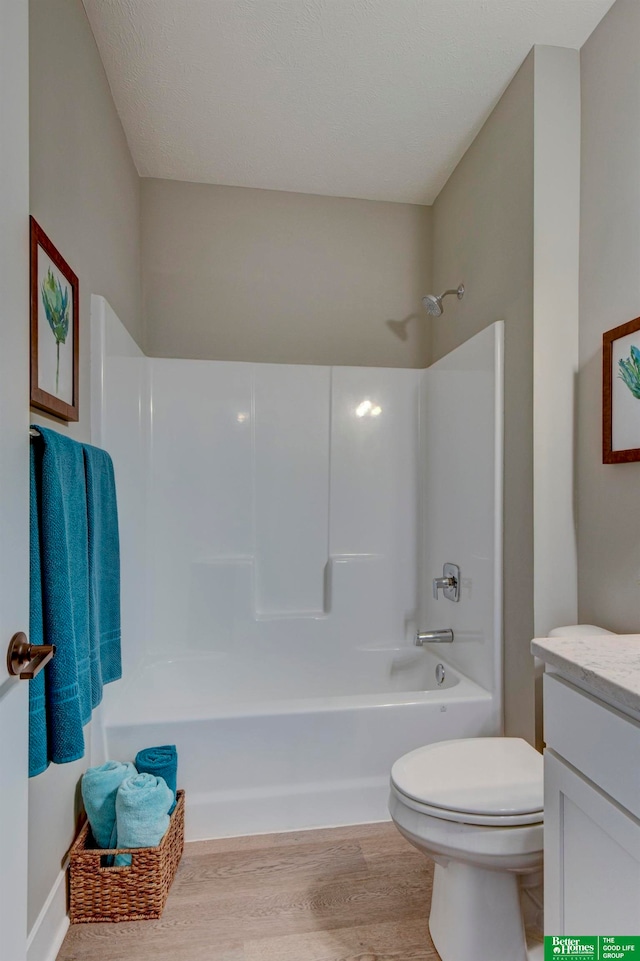 full bathroom with hardwood / wood-style flooring, shower / bath combination, vanity, and toilet