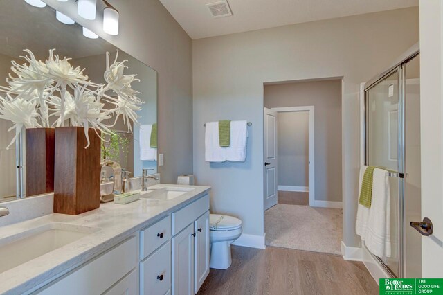 bathroom with wood-type flooring, double vanity, walk in shower, and toilet