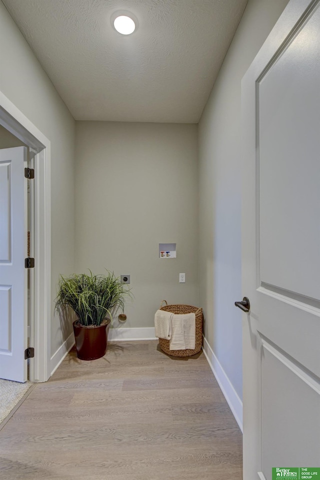 corridor with baseboards, a textured ceiling, and wood finished floors