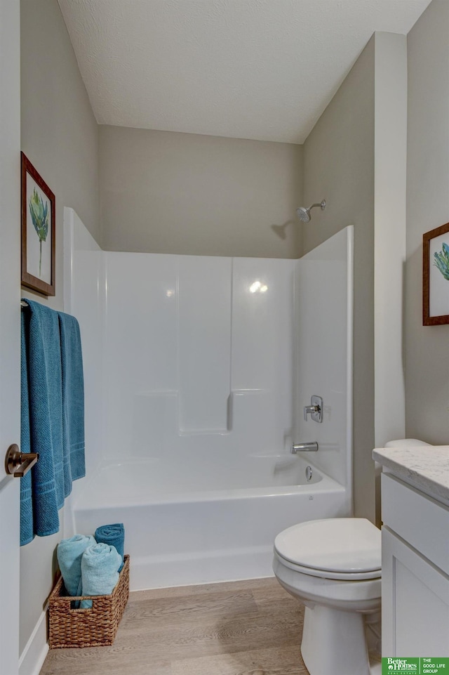bathroom with toilet, vanity,  shower combination, and wood finished floors