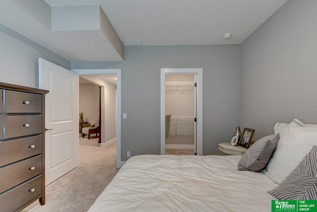 bedroom with a closet, a walk in closet, and light colored carpet