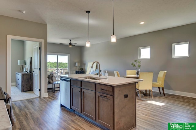 kitchen featuring an island with sink, dishwasher, dark wood-type flooring, hanging light fixtures, and sink