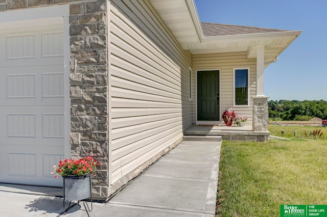 view of exterior entry featuring a garage and a yard