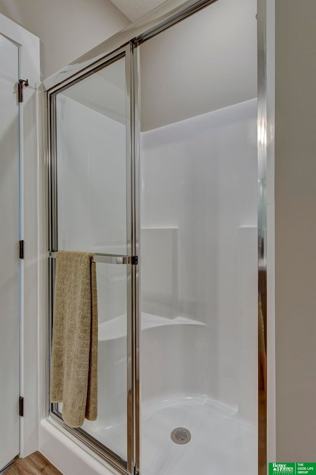 bathroom with a shower with door and hardwood / wood-style floors