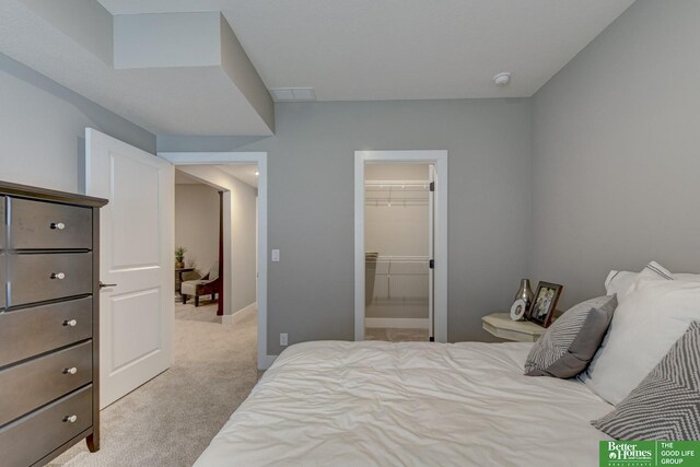 carpeted bedroom with a closet and a spacious closet