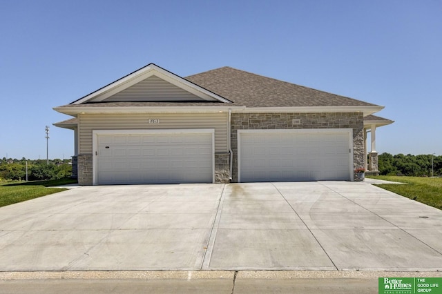 view of front of home with roof with shingles, stone siding, a garage, and concrete driveway
