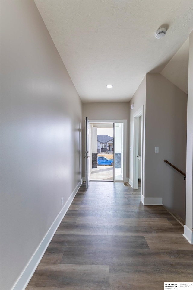 hallway with vaulted ceiling and dark hardwood / wood-style flooring