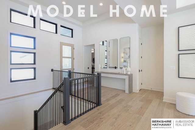 foyer with light hardwood / wood-style floors and a towering ceiling