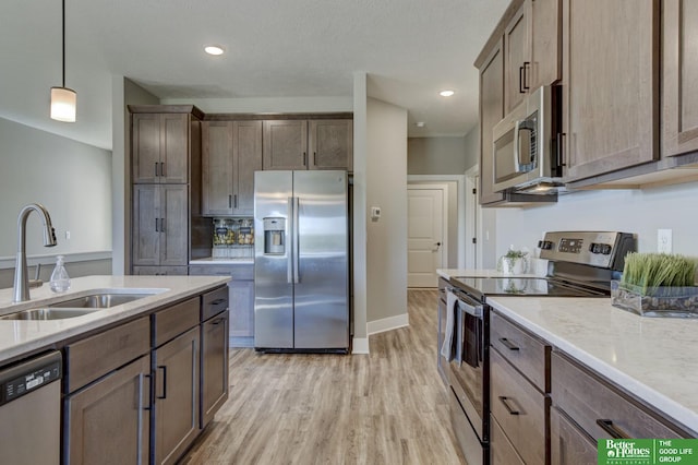 kitchen with pendant lighting, light wood-type flooring, recessed lighting, a sink, and stainless steel appliances