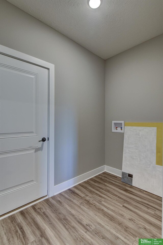 clothes washing area featuring light wood-style floors, laundry area, baseboards, and washer hookup