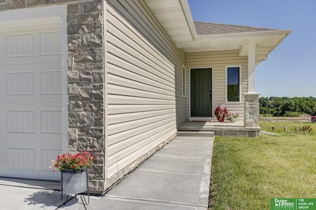 doorway to property with stone siding, a lawn, and roof with shingles