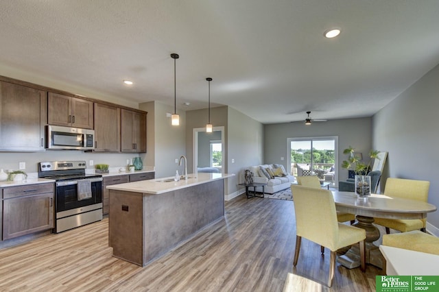 kitchen with appliances with stainless steel finishes, light wood finished floors, and light countertops