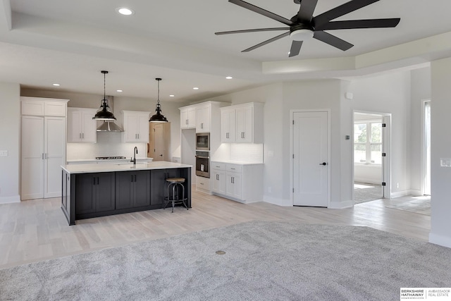 kitchen with a large island with sink, light wood-type flooring, and tasteful backsplash