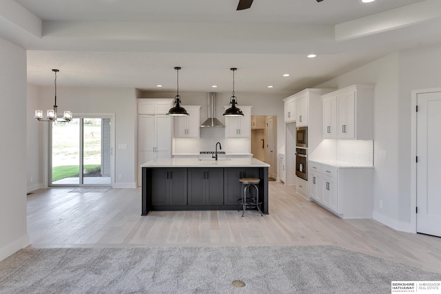 kitchen featuring light wood-type flooring, sink, wall chimney range hood, and decorative backsplash