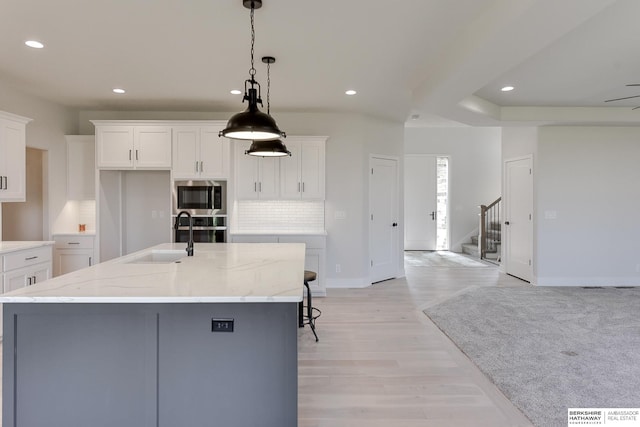 kitchen with stainless steel appliances, pendant lighting, white cabinets, and a spacious island