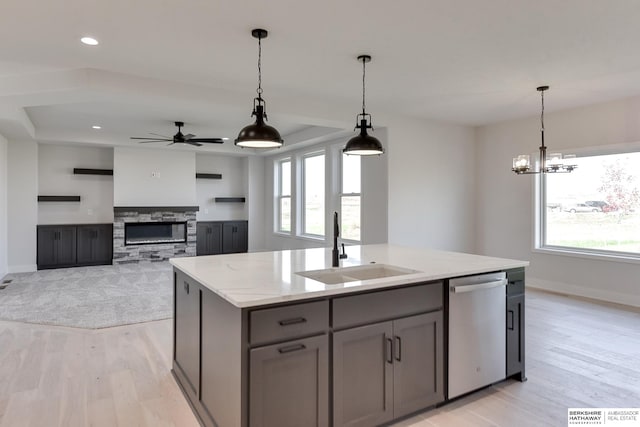 kitchen with sink, a kitchen island with sink, dishwasher, light stone countertops, and light hardwood / wood-style floors