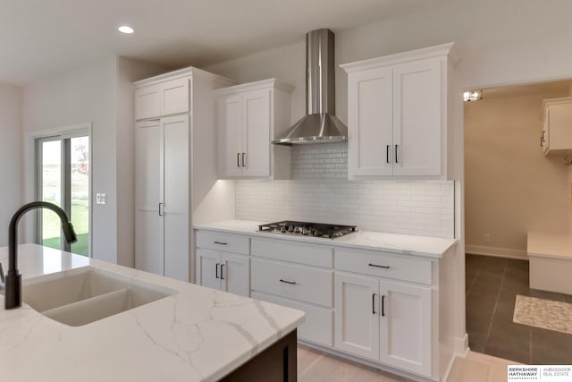 kitchen featuring light stone counters, wall chimney exhaust hood, and stainless steel gas cooktop