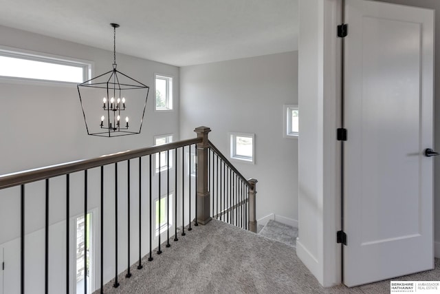 stairs with carpet floors and a chandelier