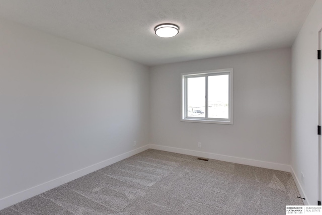 carpeted spare room featuring a textured ceiling