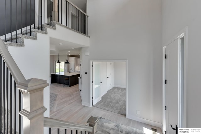 entrance foyer featuring light hardwood / wood-style floors, a high ceiling, and sink