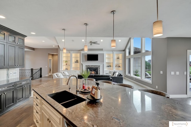 kitchen with light stone counters, sink, and hanging light fixtures