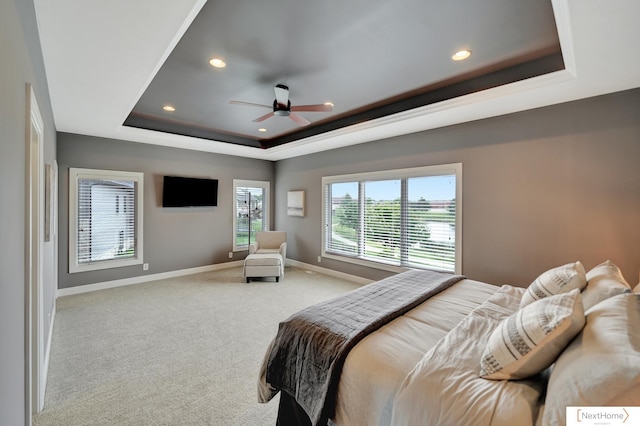 carpeted bedroom with ceiling fan and a raised ceiling