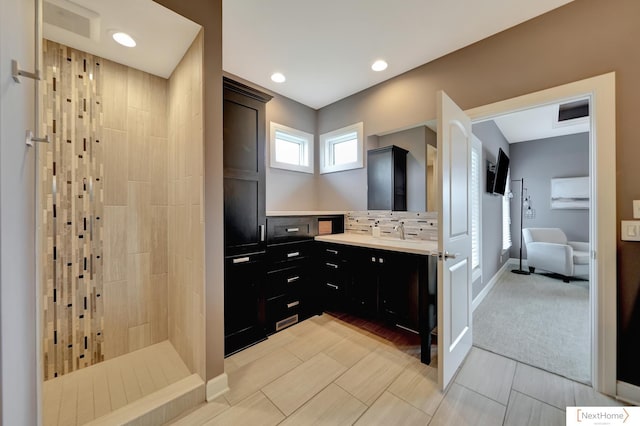 bathroom featuring tile patterned floors, vanity, a shower, and backsplash