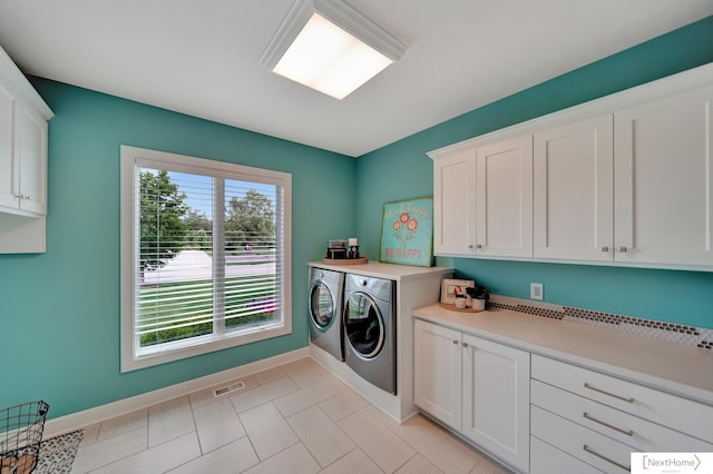 laundry area with cabinets, a wealth of natural light, and washer and dryer