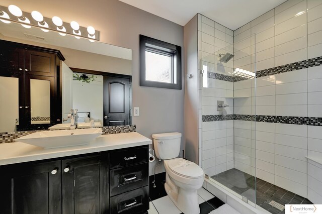 bathroom featuring a tile shower, tile patterned floors, vanity, and toilet