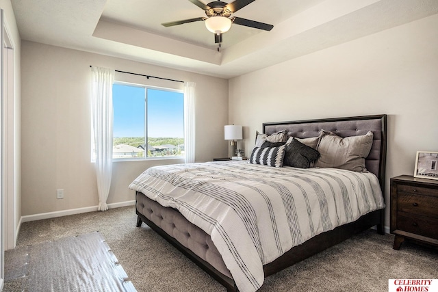 carpeted bedroom with a raised ceiling and ceiling fan