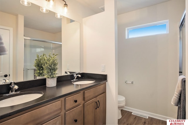 bathroom featuring vanity, toilet, a shower with shower door, and wood-type flooring