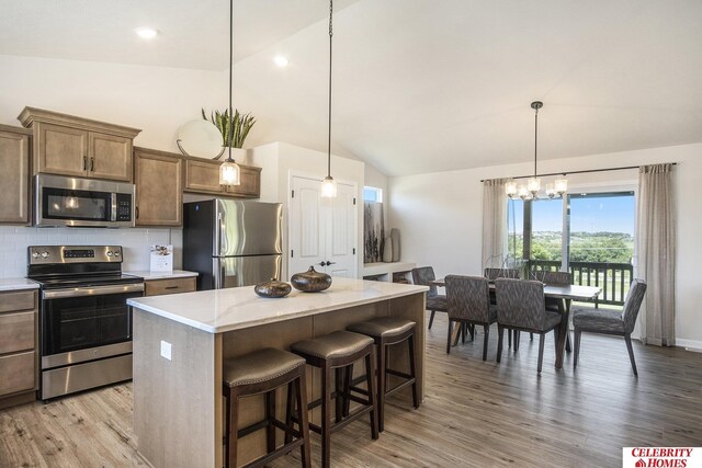 kitchen with backsplash, a kitchen island, stainless steel appliances, and vaulted ceiling