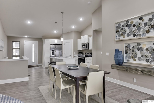 dining room featuring sink, high vaulted ceiling, and light hardwood / wood-style floors