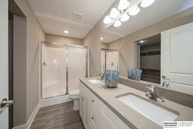 bathroom with hardwood / wood-style floors, vanity, toilet, and walk in shower