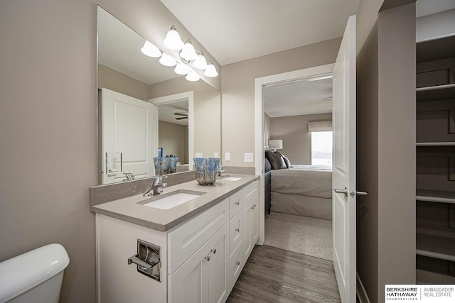 bathroom with hardwood / wood-style floors, vanity, toilet, and ceiling fan